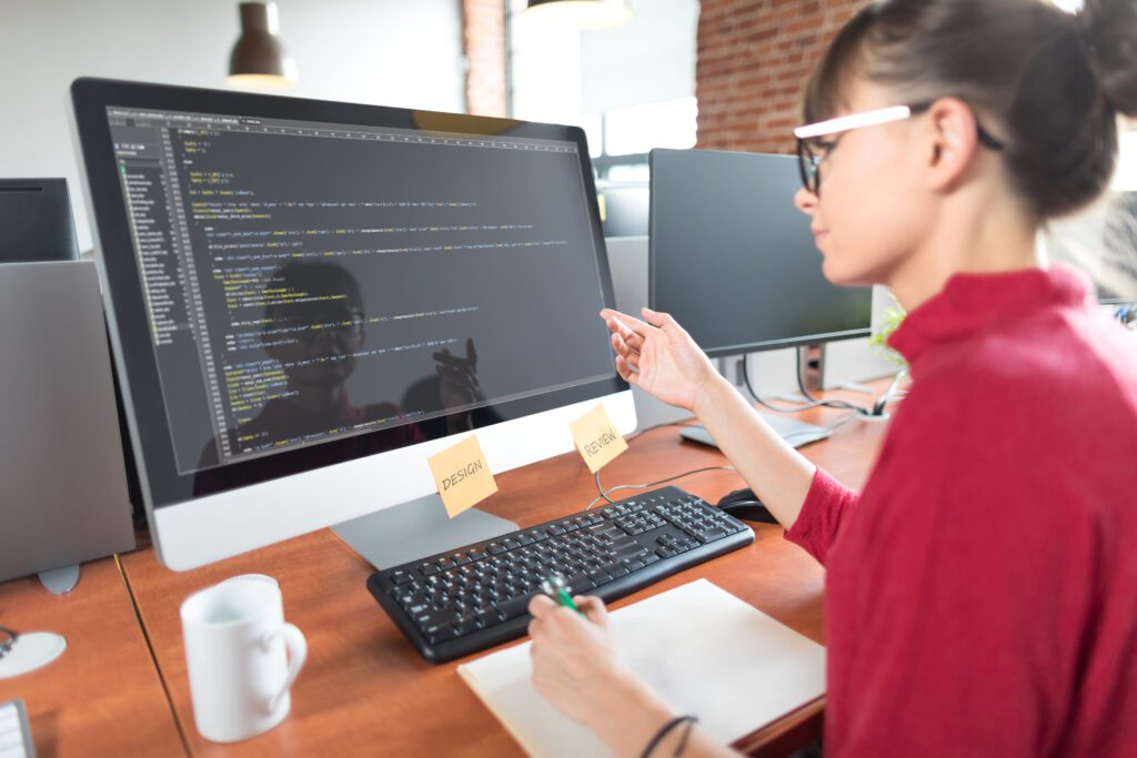 Woman in red formal suit looking at the monitor.